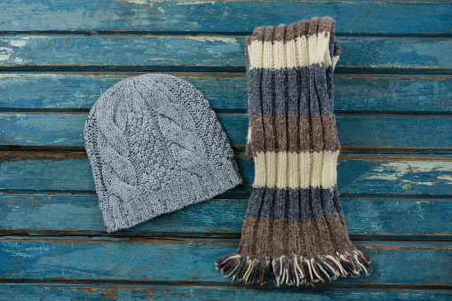 Overhead view of knit hat and scarf on wooden table