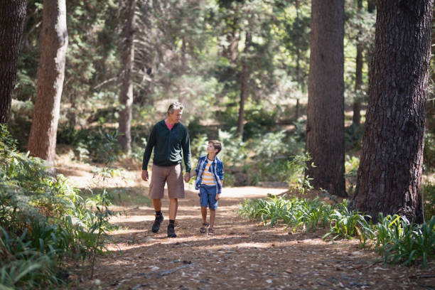 istock Father and son walking amidst trees in forest 829105278