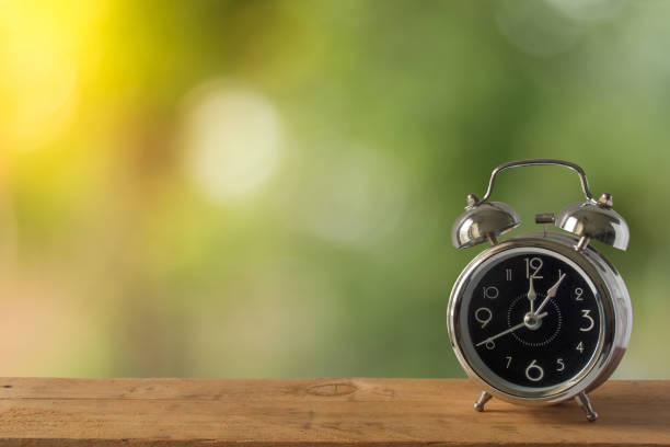 istock alarm clock on wooden table and nurture bokeh background 829150304