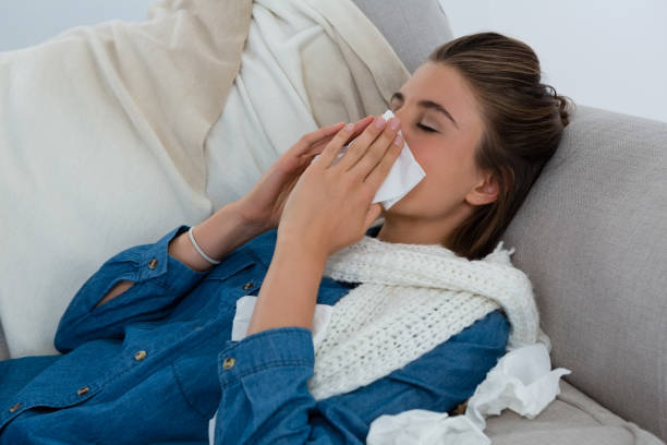 istock Young woman rubbing nose while lying on sofa 829164550