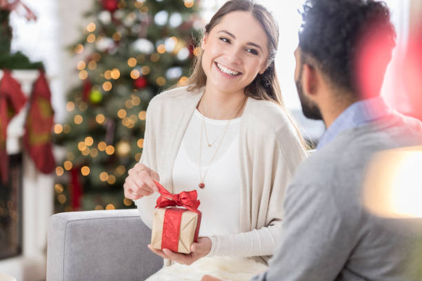 istock Young woman opens Christmas present from boyfriend 829170210