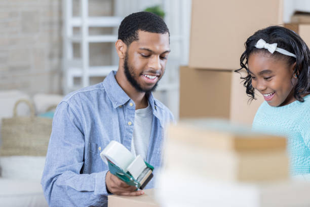 istock Father and young daughter tape up moving boxes together 829171792