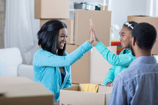 istock Young mother gives young daughter high five while packing moving boxes 829171882