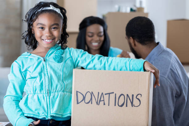 istock Little girl smiles for the camera while holding donations box 829171888