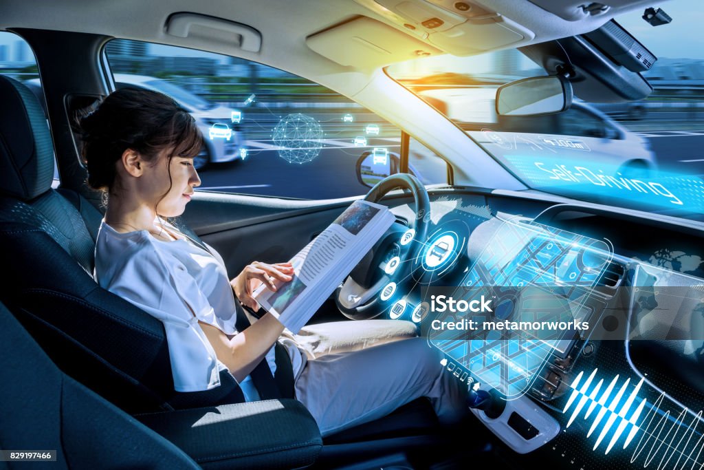 young woman reading a magazine in a autonomous car. driverless car. self-driving vehicle. heads up display. automotive technology. Driverless Transport Stock Photo