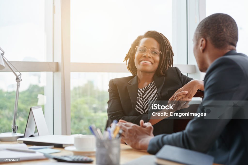 Chatting with colleague Beautiful smiling African-American business lady chatting with coworker African-American Ethnicity Stock Photo