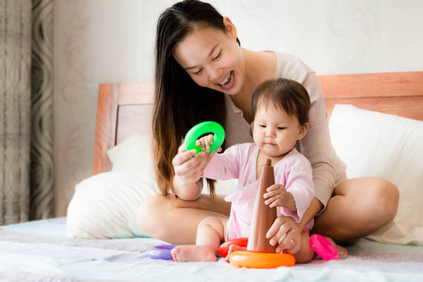 istock Happy mother teaches 2 year old daughter coordination skills using plastic hoop toys 829206500
