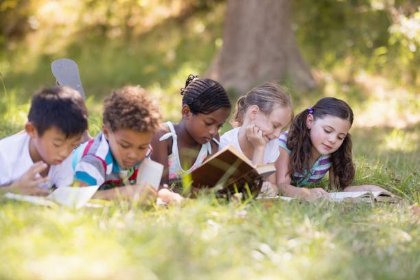 istock Group of friends reading book while lying on grassy field 829210850