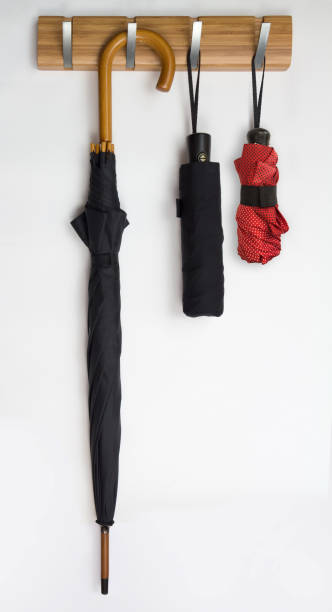 istock Two black men's umbrellas hang on hook rack, white background 829227374