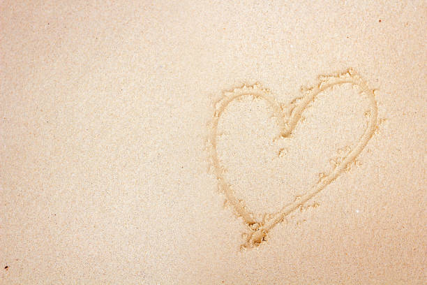 istock Heart drawn in the sand top view. 829280760