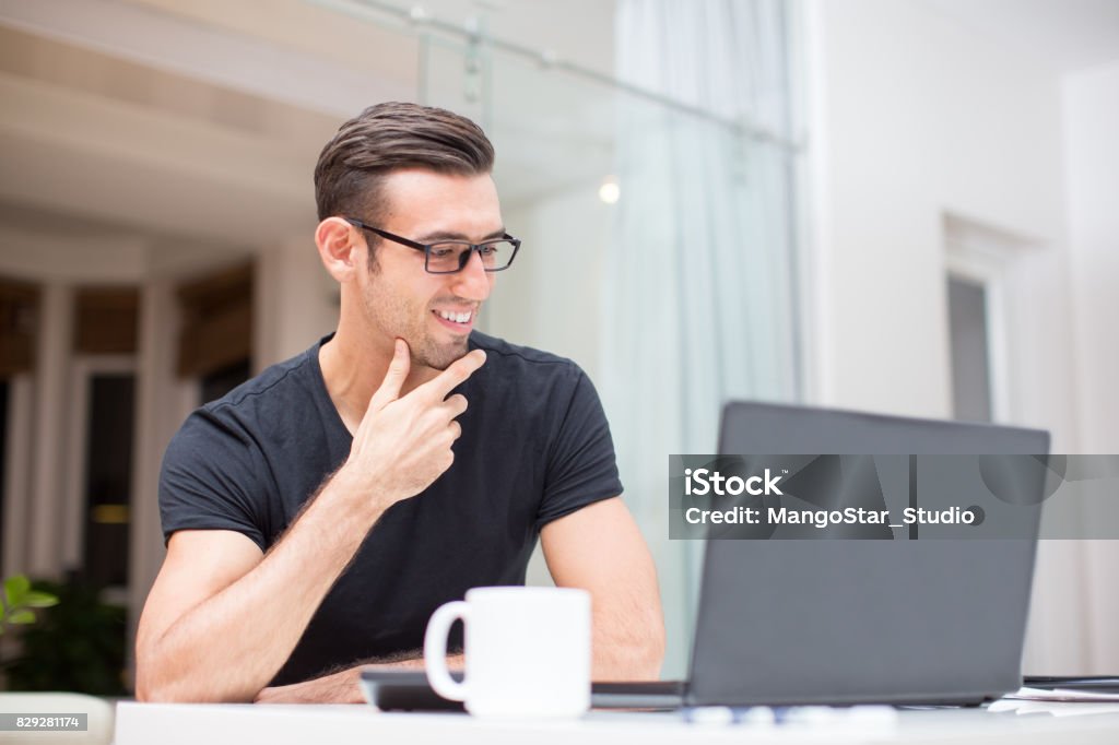 Lächelnder junge Mann arbeiten am Laptop zu Hause - Lizenzfrei Akademisches Lernen Stock-Foto