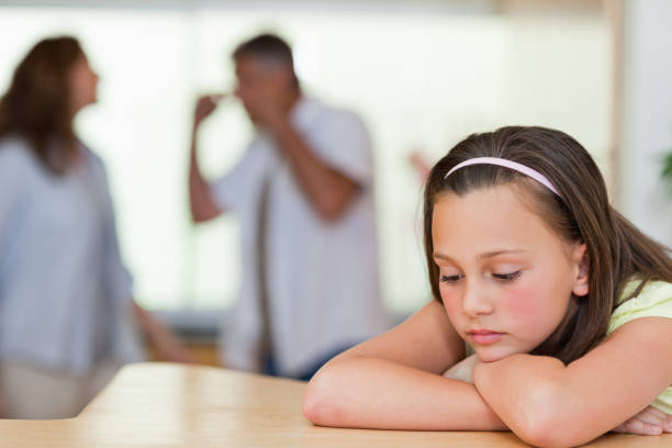 istock Sad girl with her fighting parents behind her 829281514