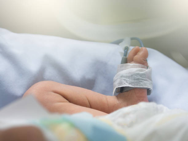 Newborn baby feet and leg with oxygen saturation monitor or pulse oximeter machine, lay in incubator for warming and treated at intensive care unit in a hospital after preterm birth Newborn baby feet and leg with oxygen saturation monitor or pulse oximeter machine, lay in incubator for warming and treated at intensive care unit in a hospital after preterm birth maternity ward stock pictures, royalty-free photos & images