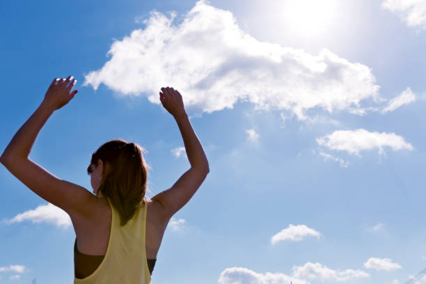 istock Attractive young woman stretching her arms while standing against a deep blue sky, exercising on a sunny day. 829302874