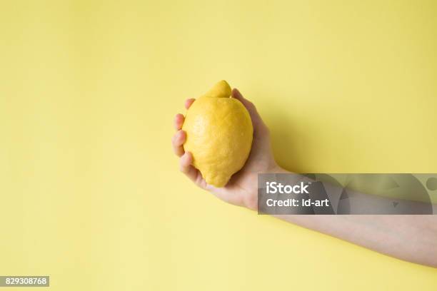 Lemon In Womans Hand On A Yellow Background Stock Photo - Download Image Now - Lemon - Fruit, Hand, Human Hand