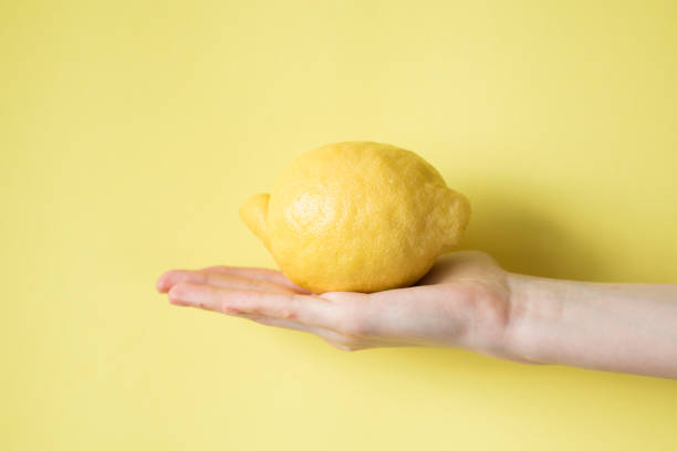 istock Lemon in woman's hand on a yellow background 829308850