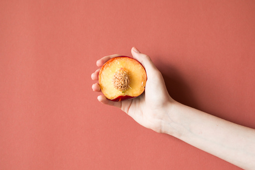 hand with a fresh juicy peach on a red background