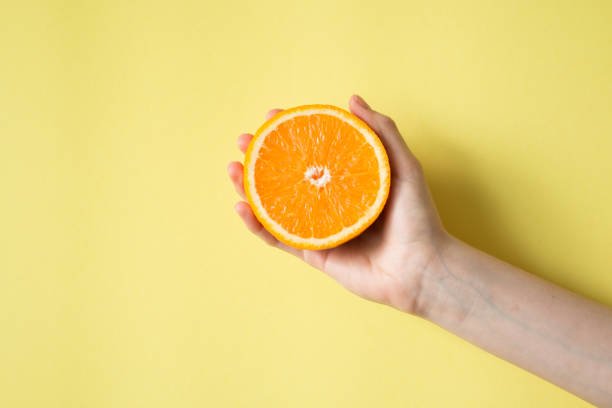 istock Hand holding orange on yellow background food concept 829309794
