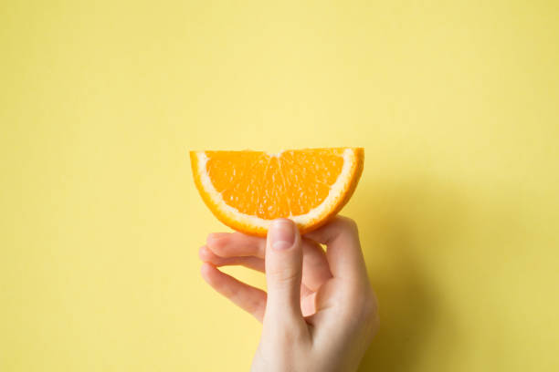 istock Hand holding orange on yellow background food concept 829310022