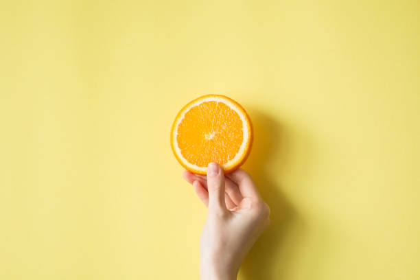 istock Hand holding orange on yellow background food concept 829310152