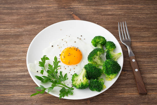 istock Fried eggs with broccoli and greens  on a wooden table 829318184