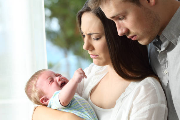 müde verzweifelten eltern und baby weint - verwirrung fotos stock-fotos und bilder