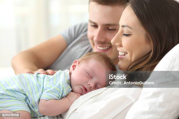 Parents Watching Their Baby Sleeping Stock Photo - Download Image Now - Newborn, Father, Couple - Relationship