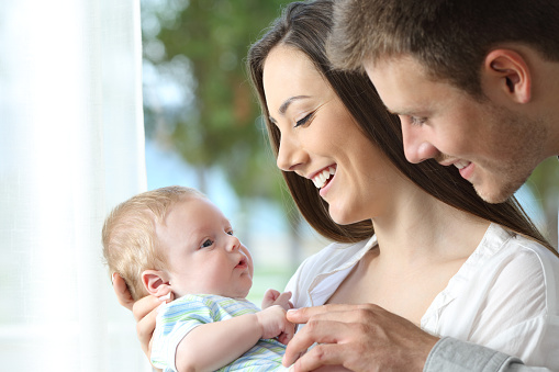 Proud parents holding and playing with their baby at home