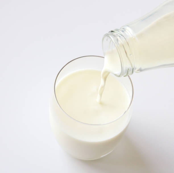istock Glass bottle pouring milk into a glass on white background 829407342