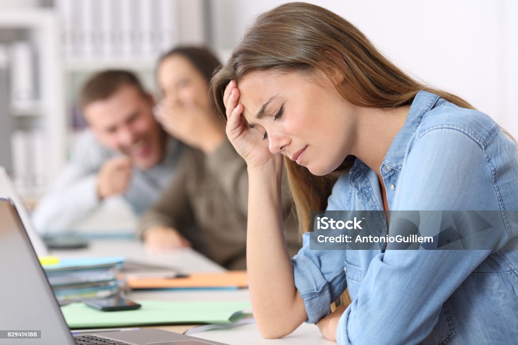 Bullying victim being criticized at office Side view portrait of a bullying victim being criticized at office Bullying Stock Photo