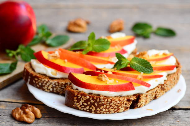 istock Easy sandwiches with cream cheese, fresh nectarines, walnuts and mint on a plate and on a vintage wooden table. Cream cheese sandwich recipe for kids. Rustic style. Closeup 829421884