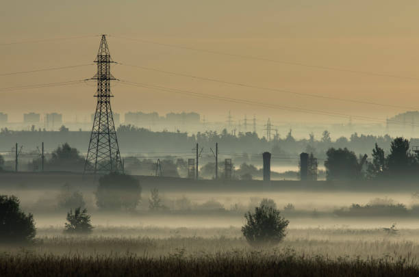 Tower of power lines in the pre-dawn fog on the outskirts of the city