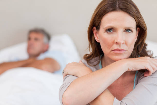 istock Sad woman on the bed with husband in background 829427686
