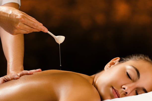 therapeut gießen ayurvedischen öl auf weibliche zurück. - ayurveda massaging spa treatment massage oil stock-fotos und bilder