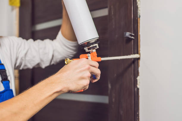 istock Young handyman installing door with an mounting foam in a room 829431464
