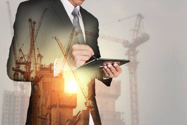 istock businessman working with tablet, construction crane, building as industrial concept. 829434810