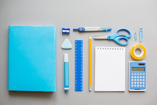 Blue school supplies on grey background, knolling.