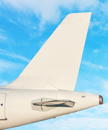 Airplane tail fin - sky with white clouds in background