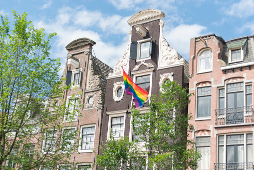 Horizontal color image of Amsterdam architecture with a rainbow flag.