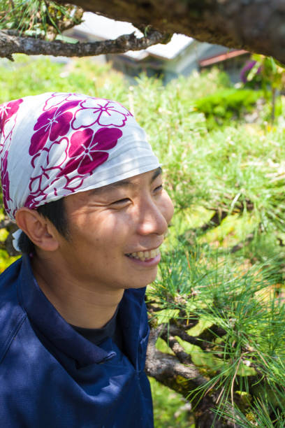 istock Young Japanese Gardener pruning pine tree 829488586