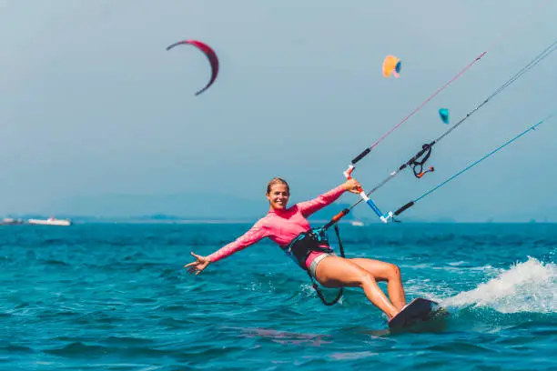 Young female kiteboarder on the water, active summer holidays by the sea, windy weather, surfing and kiteboarding, adrenaline sports