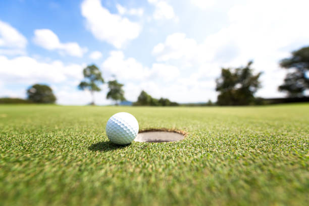 istock Golf ball near hole, background blue sky 829546696