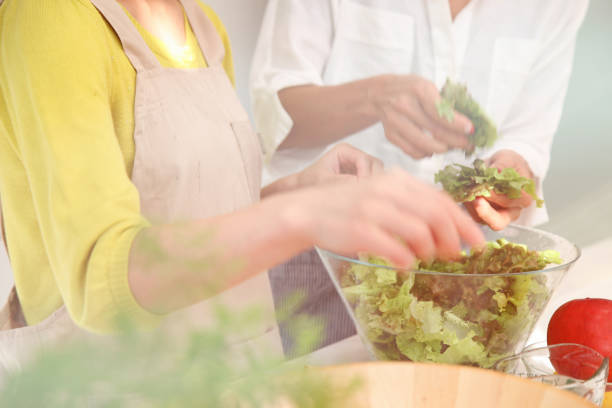 istock two women preparing salad in kitchen 829564016