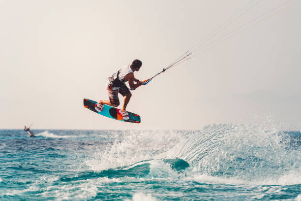 Flying kite surfer Young athlete practising kiteboarding, success in sports, taking care of his body, enjoying aquatic sports, summer vacations, young male sportsman, adrenaline sports kiteboard stock pictures, royalty-free photos & images