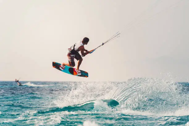 Young athlete practising kiteboarding, success in sports, taking care of his body, enjoying aquatic sports, summer vacations, young male sportsman, adrenaline sports