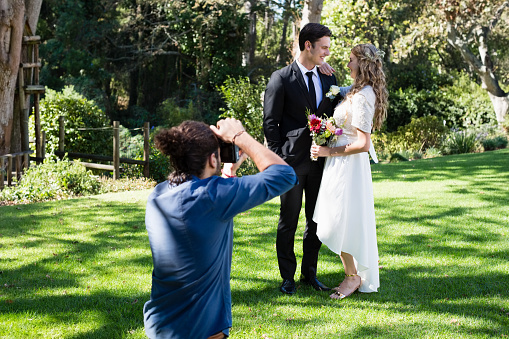 Photographer taking photo of newly married couple in park