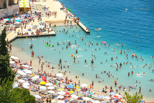 Neum, Bosnia and Herzegovina - July 16, 2017 : A view of the town waterfront and people swimming and sunbathing on the beach in Neum, Bosnia and Herzegovina.