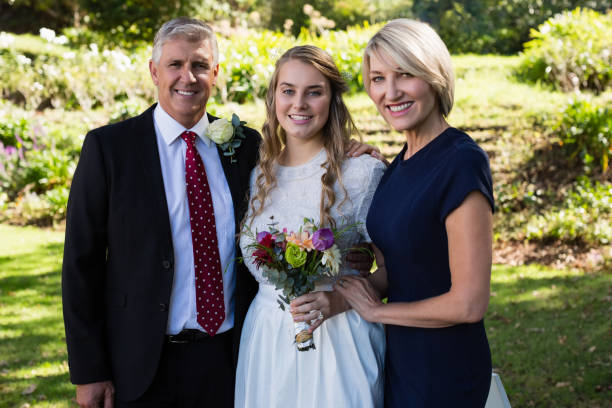istock Bride standing with her parents in park 829612134