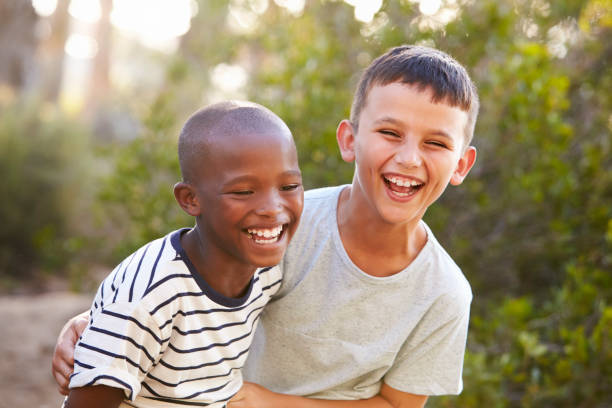 porträt von zwei jungen, die sich im freien umarmen und hart lachen - laughing children stock-fotos und bilder