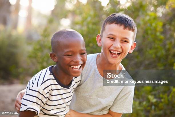 Retrato De Dos Muchachos Abrazándose Y Riendo Duro Al Aire Libre Foto de stock y más banco de imágenes de Niño